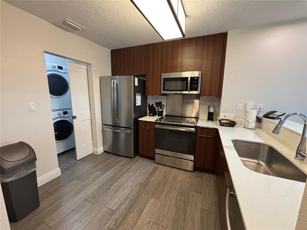 A kitchen features dark wood cabinets, stainless steel appliances, white countertops, and wood-look tile flooring — 14501 GROVE RESORT AVENUE UNIT 2532, WINTER GARDEN, FL