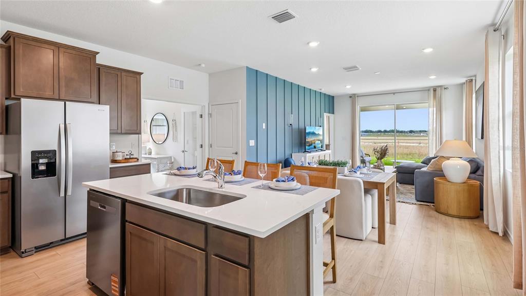 A kitchen with a center island and stainless steel appliances opens to a living area — 8782 PINECREST TRAIL, WILDWOOD, FL