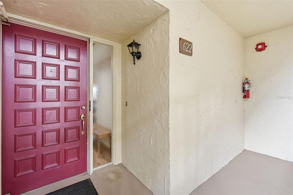 A red front door with a glass sidelight stands next to a unit numbered 622 — 700 STARKEY ROAD UNIT 622, LARGO, FL