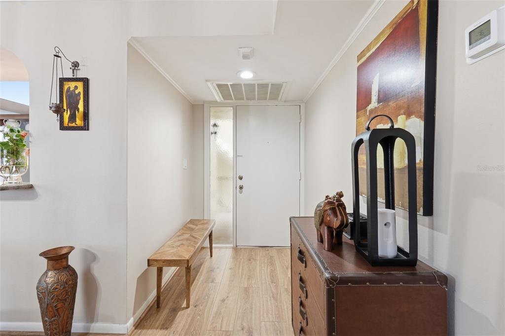 An entryway features wood-look flooring, a wooden bench, a chest of drawers, and a door — 700 STARKEY ROAD UNIT 622, LARGO, FL
