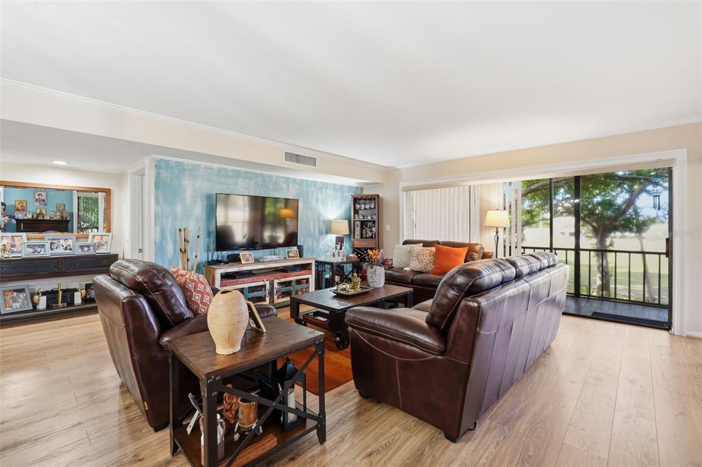A living room features brown leather furniture, a blue accent wall, and a sliding glass door — 700 STARKEY ROAD UNIT 622, LARGO, FL