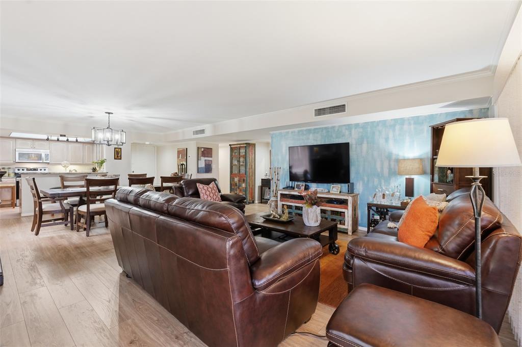 A living room with brown leather furniture, wood-look flooring, and a blue accent wall — 700 STARKEY ROAD UNIT 622, LARGO, FL