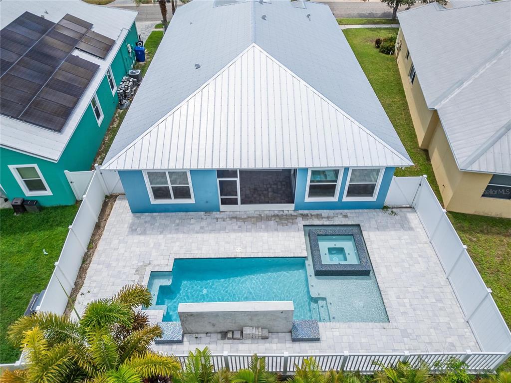 An aerial view shows a blue house with a metal roof, pool, and spa — 567 BIMINI BAY BOULEVARD, APOLLO BEACH, FL