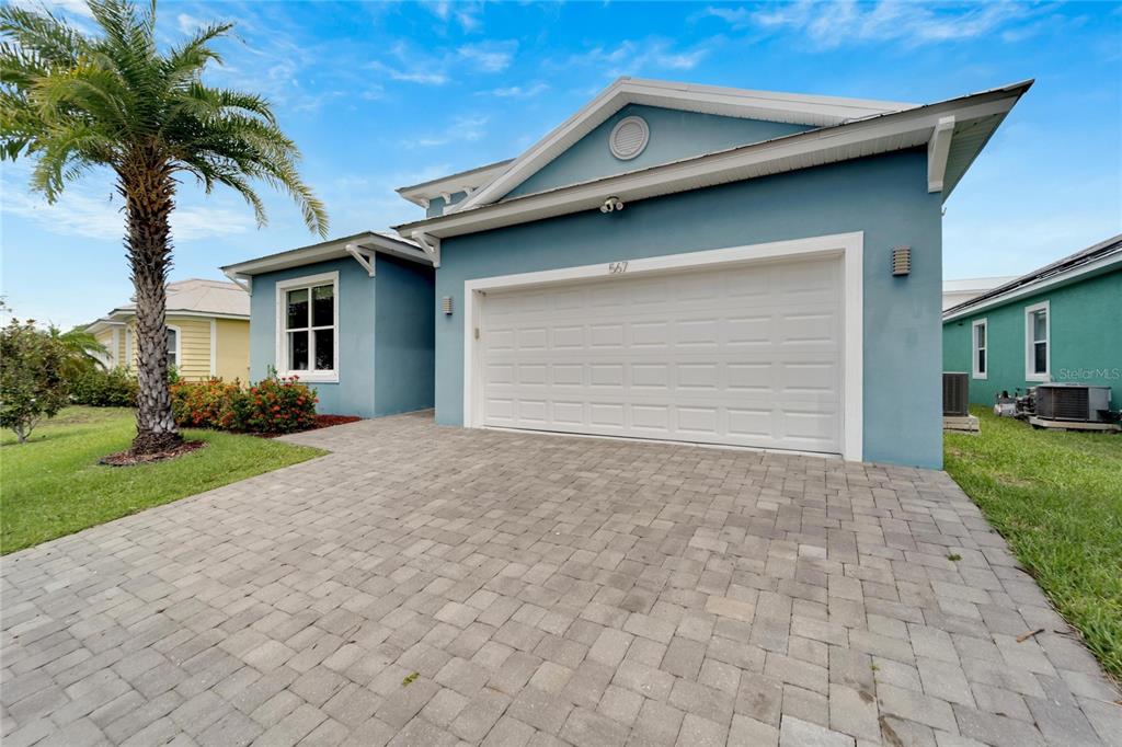 A blue house with a white garage door and a paved driveway under a blue sky — 567 BIMINI BAY BOULEVARD, APOLLO BEACH, FL