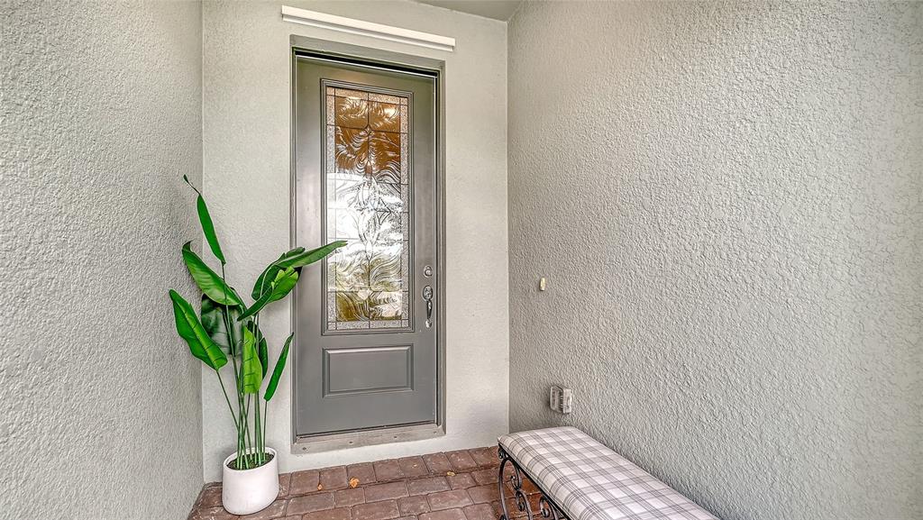A gray front door with a decorative glass insert sits on a paved entryway porch — 3355 ANCHOR BAY TRAIL, BRADENTON, FL