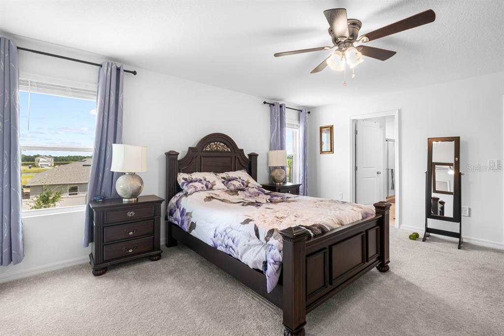 A bedroom features a dark wood bed frame, two matching nightstands, and light purple curtains — 13524 CAMELOT CT, PARRISH, FL