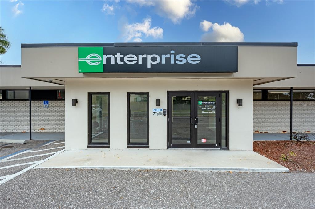 The exterior of an Enterprise Rent-A-Car office building with a glass entrance and brick walls — 313 18TH AVE S STREET, ST PETERSBURG, FL