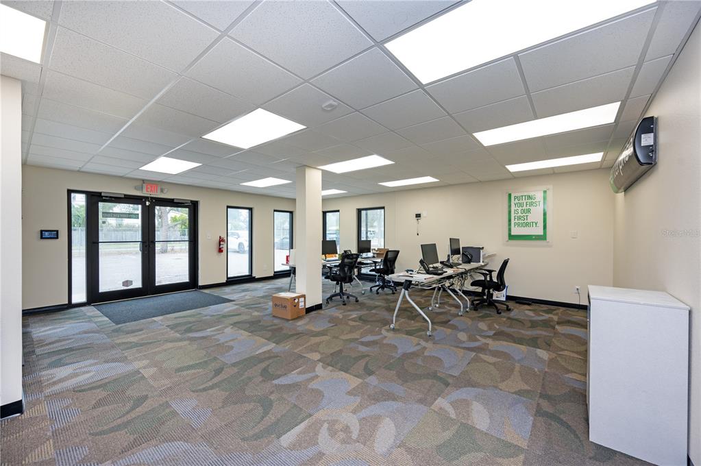 An office interior features a patterned carpet, drop ceiling, and several desks with computer monitors — 313 18TH AVE S STREET, ST PETERSBURG, FL
