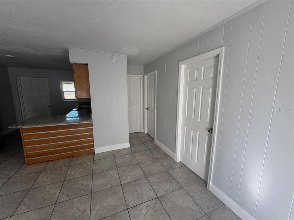 A kitchen with a breakfast bar and tiled floors leads to a hallway with doors — 1392 KING STREET UNIT 1394, BARTOW, FL