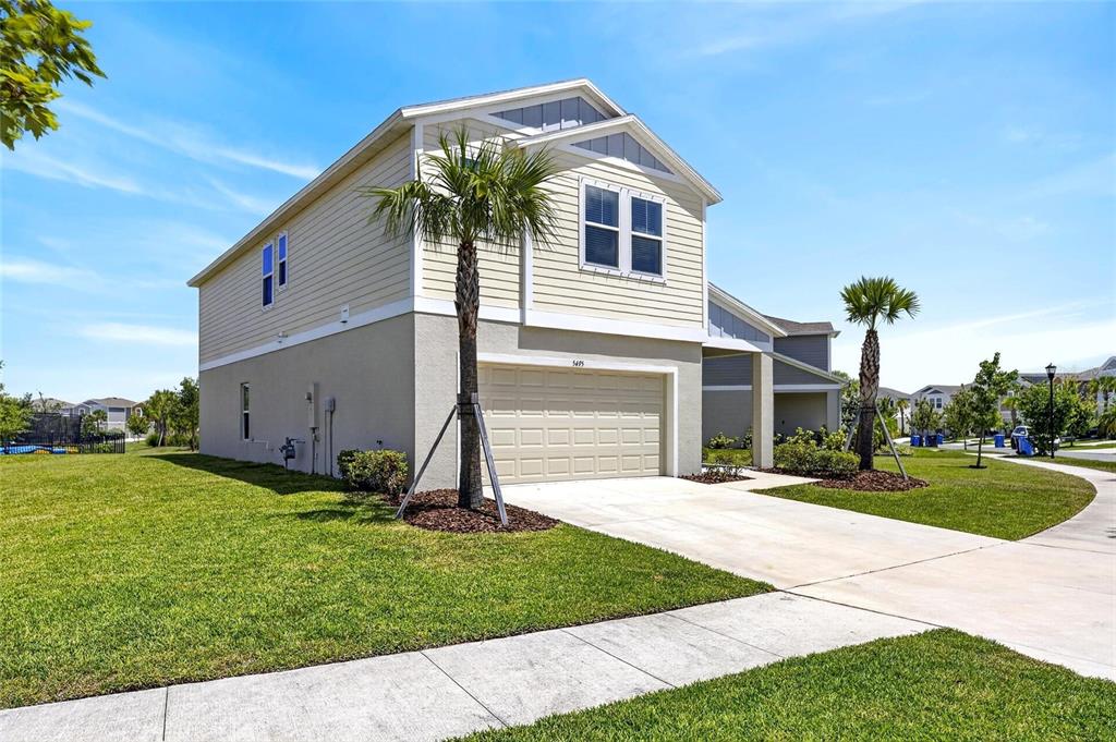 A two-story house with beige siding, a two-car garage, and two palm trees in front — 5495 SUMMER SUNSET DRIVE, APOLLO BEACH, FL
