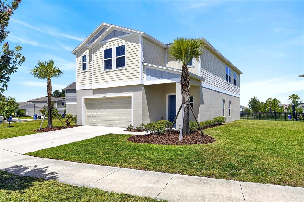 A two-story house with light-colored siding, a two-car garage, and two palm trees in front — 5495 SUMMER SUNSET DRIVE, APOLLO BEACH, FL