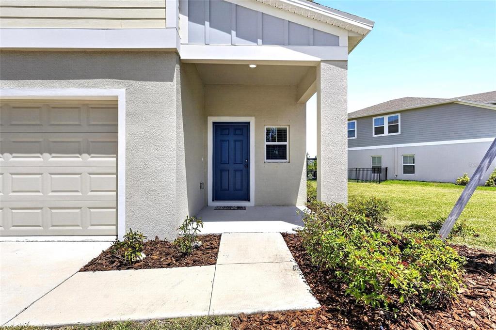 The exterior of a house features a blue front door, a garage, and a walkway — 5495 SUMMER SUNSET DRIVE, APOLLO BEACH, FL