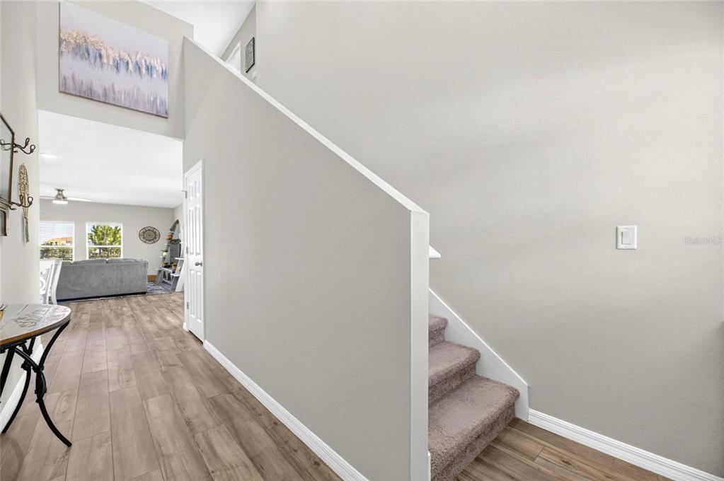 A staircase with carpeted steps sits beside a hallway leading to a living room — 5495 SUMMER SUNSET DRIVE, APOLLO BEACH, FL