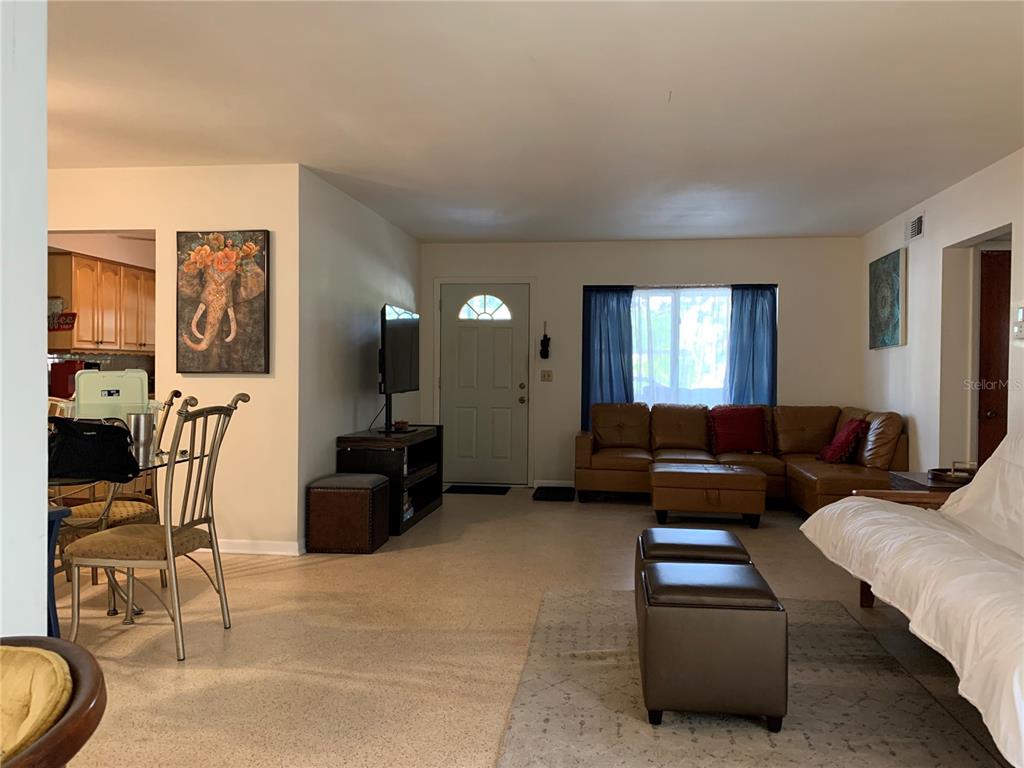 A living room with a brown sectional sofa, a dining area, and a front door — 1750 DRUID ROAD E, CLEARWATER, FL