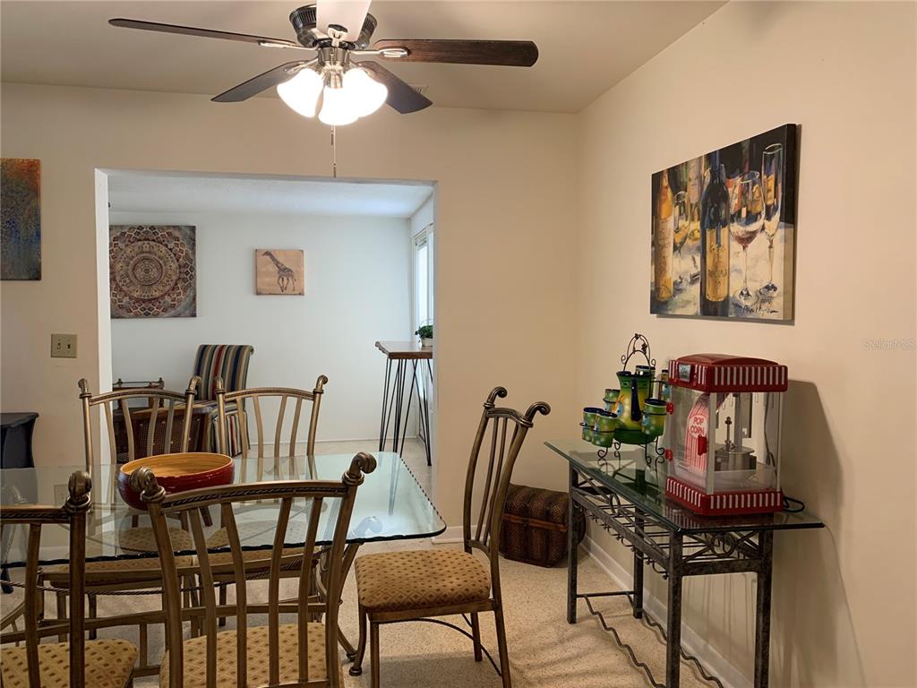 A dining room features a glass-topped table, metal chairs, and a popcorn machine on a console — 1750 DRUID ROAD E, CLEARWATER, FL