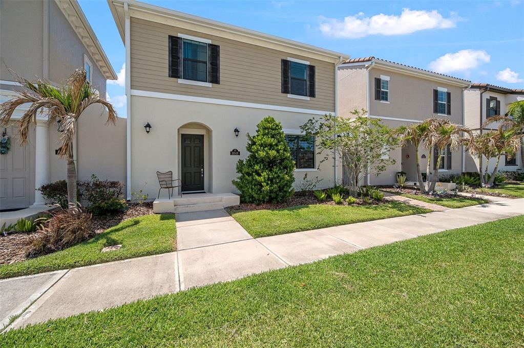 A two-story tan house with a front walkway, small lawn, and palm trees — 8048 GULLEN DRIVE, MELBOURNE, FL