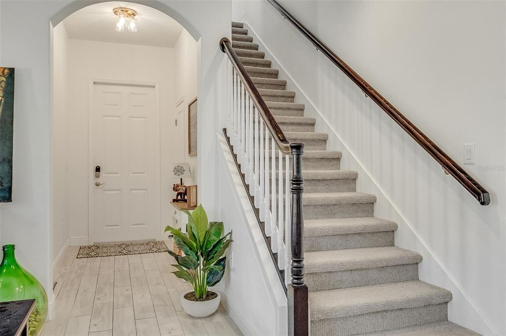 An entryway features a carpeted staircase with a wooden handrail and a white front door — 8048 GULLEN DRIVE, MELBOURNE, FL
