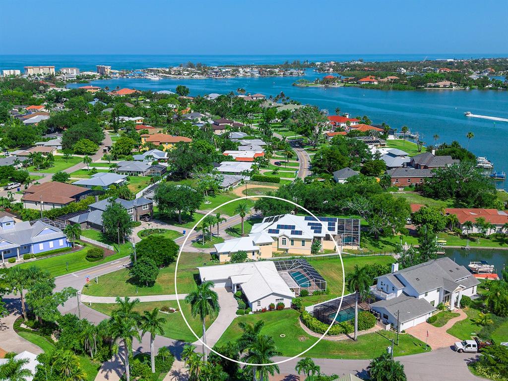 An aerial view of a coastal residential neighborhood featuring a house with a pool enclosure — 396 BAYSHORE DRIVE, VENICE, FL
