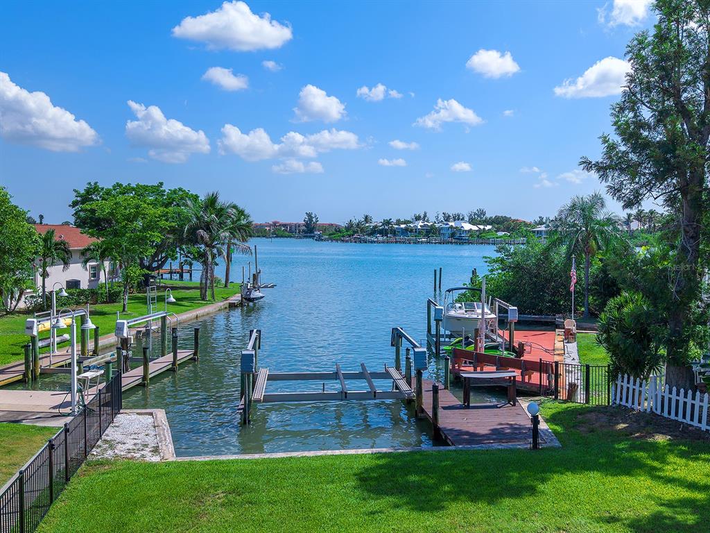 A view of a canal with private boat docks and a boat lift from a lawn — 396 BAYSHORE DRIVE, VENICE, FL