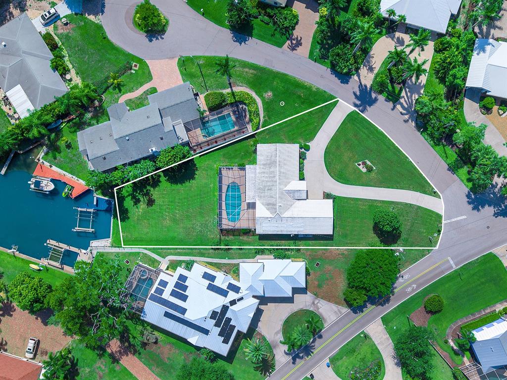 An aerial view shows a residential property with a pool, lawn, and waterfront access — 396 BAYSHORE DRIVE, VENICE, FL
