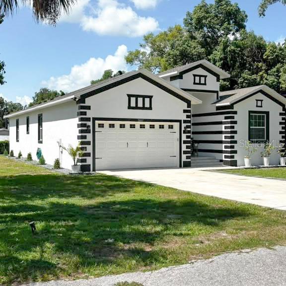 A single-story house features white stucco walls with bold black trim and a garage — 36842 CENTER AVE, DADE CITY, FL