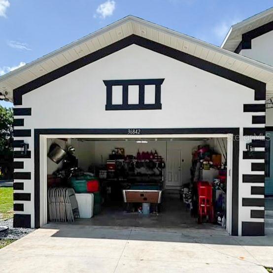 A two-car garage with a white exterior, black trim, and a pool table inside — 36842 CENTER AVE, DADE CITY, FL