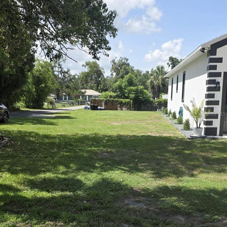 A grassy side yard sits next to a white house with black trim — 36842 CENTER AVE, DADE CITY, FL