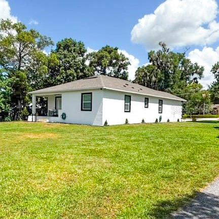 A white, single-story house with a hip roof sits on a large grassy lot — 36842 CENTER AVE, DADE CITY, FL