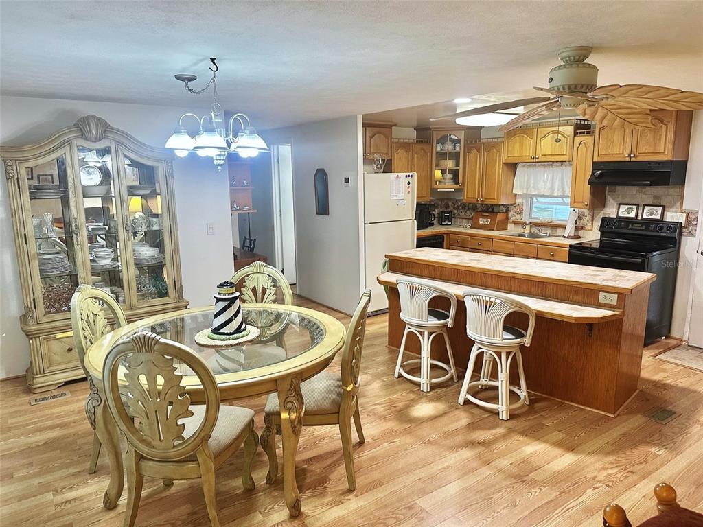 A dining area with a glass-topped table and hutch adjacent to a kitchen with wood cabinets — 11211 101ST STREET UNIT 93, LARGO, FL