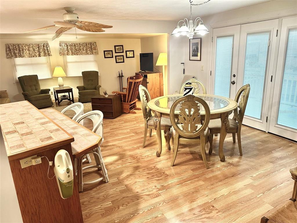 A dining area with a glass table and a living space with wood-look flooring — 11211 101ST STREET UNIT 93, LARGO, FL