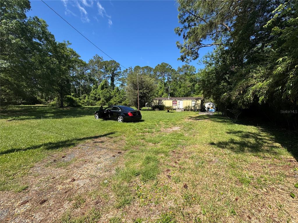 A black sedan is parked on a large, grassy lot in front of a mobile home — 2981 PACETTI ROAD, ST AUGUSTINE, FL