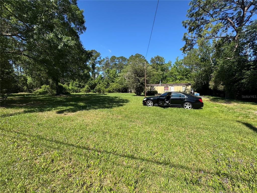 A black sedan is parked on a grassy lot in front of a mobile home — 2981 PACETTI ROAD, ST AUGUSTINE, FL