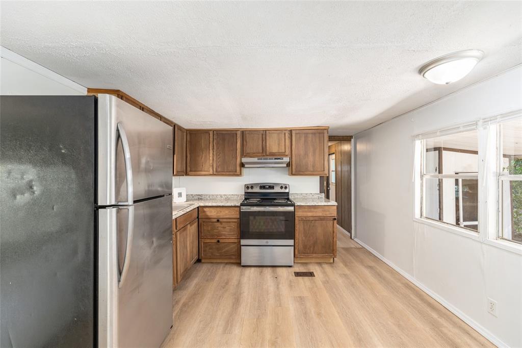 A kitchen with wood cabinets, stainless steel appliances, and light wood-look flooring — 2901 SW 91ST STREET, OCALA, FL