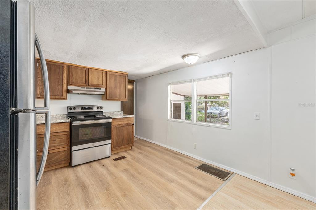 A kitchen with wood cabinets, stainless steel appliances, light wood flooring, and a large window — 2901 SW 91ST STREET, OCALA, FL