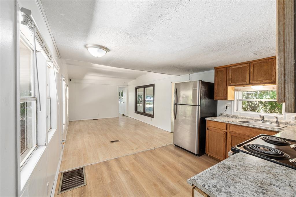 A kitchen with wood cabinets and stainless steel appliances opens into a spacious living area — 2901 SW 91ST STREET, OCALA, FL