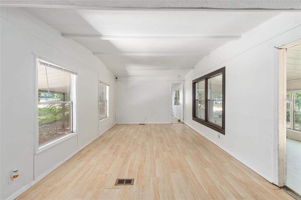 An empty room with white walls, light wood-look flooring, and several windows — 2901 SW 91ST STREET, OCALA, FL
