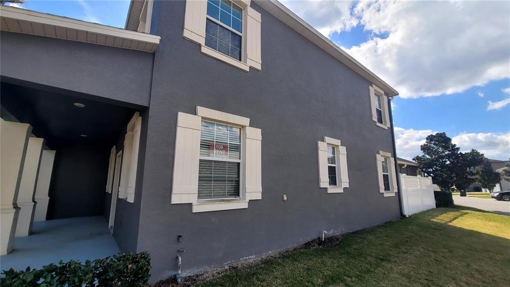 The exterior of a two-story gray house features white shutters and a covered entryway — 7612 FAIRGROVE AVENUE, WINDERMERE, FL