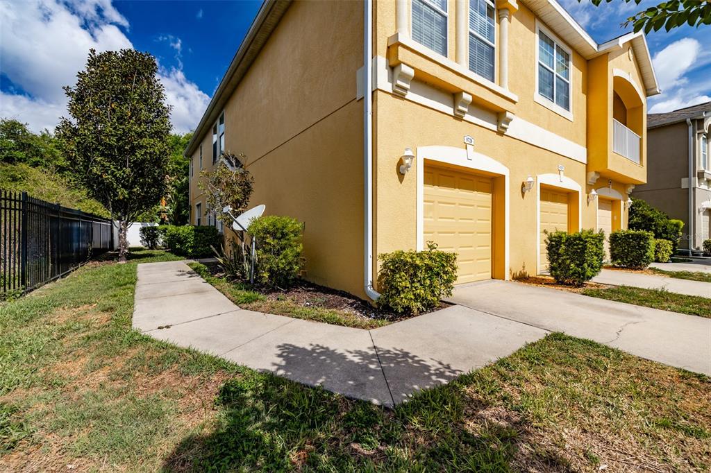 An exterior view of a yellow two-story townhouse with a garage and concrete driveway — 8726 MOONLIT MEADOWS LOOP, RIVERVIEW, FL
