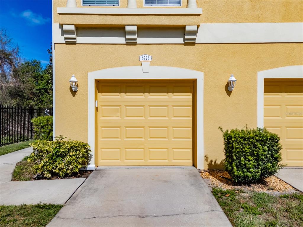 A yellow stucco house exterior features a brown front door and a manicured hedge — 8726 MOONLIT MEADOWS LOOP, RIVERVIEW, FL