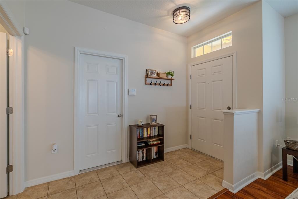 A living room with a sectional sofa, hardwood floors, and an open kitchen area — 8726 MOONLIT MEADOWS LOOP, RIVERVIEW, FL