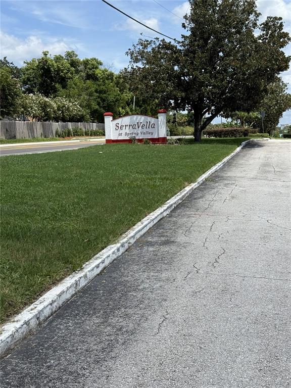 A sign for SerraVella at Spring Valley stands on a grassy lawn beside a road — 305 WYMORE ROAD UNIT # 107, ALTAMONTE SPRINGS, FL