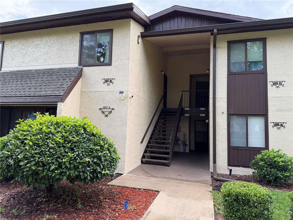 An exterior view of a two-story apartment building with a central staircase and landscaping — 687 MIDWAY DRIVE UNIT A, OCALA, FL