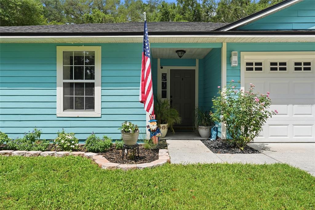 A teal, single-story house with a white garage door and a concrete driveway — 17686 NW 239TH TERRACE, HIGH SPRINGS, FL