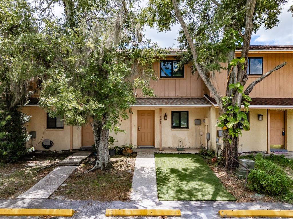 A two-story townhouse exterior features tan siding, brown doors, and concrete walkways — 4008 OAK LIMB, TAMPA, FL