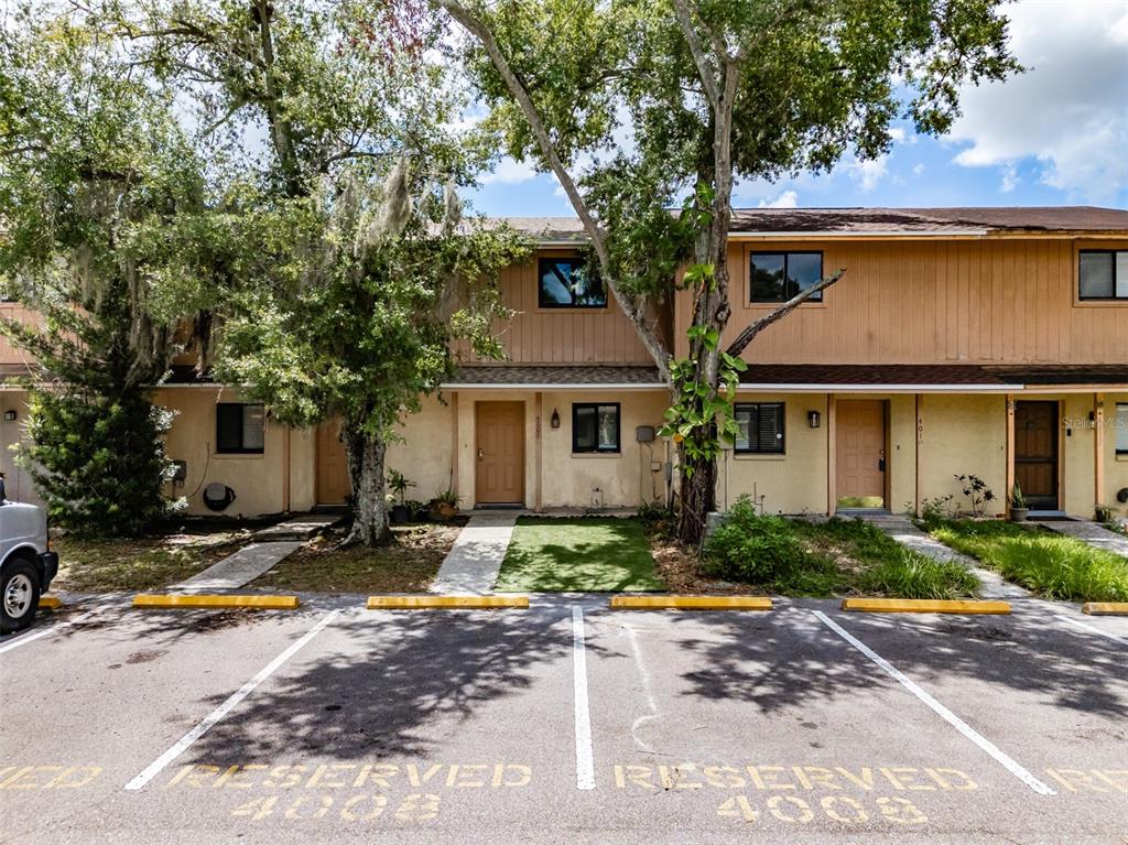 A row of two-story townhouses with tan siding and reserved parking spaces in the foreground — 4008 OAK LIMB, TAMPA, FL