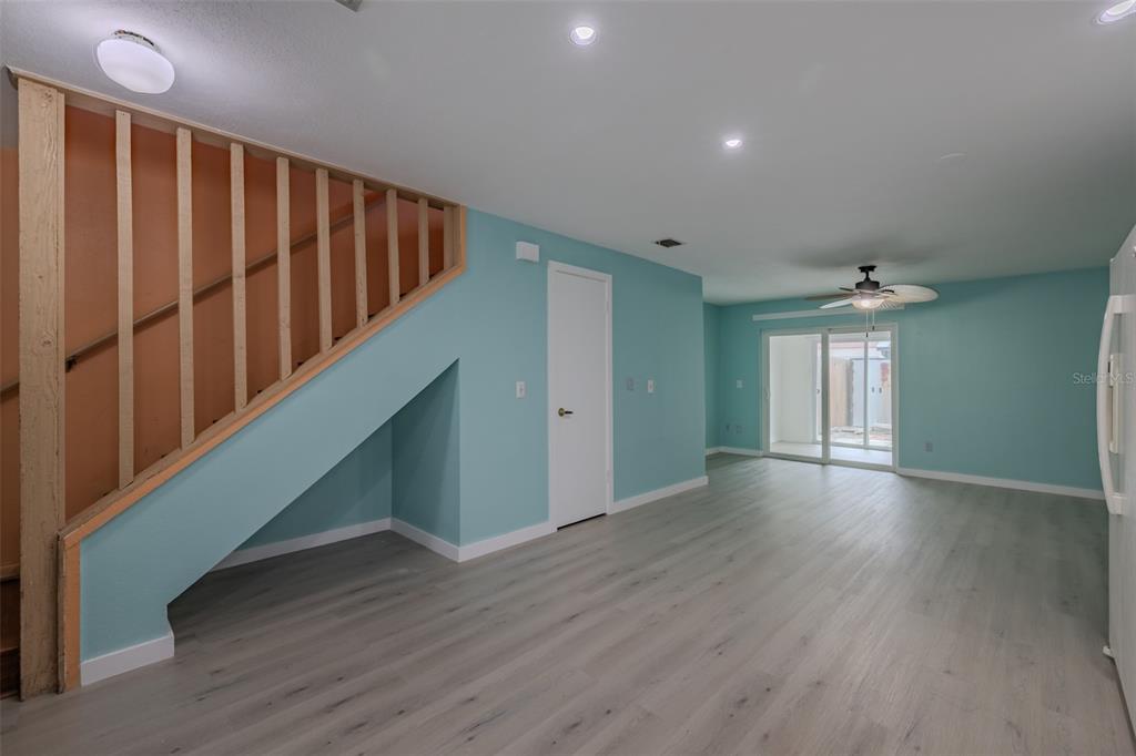 A living room with light blue walls, wood-look flooring, a staircase, and a sliding glass door — 4008 OAK LIMB, TAMPA, FL
