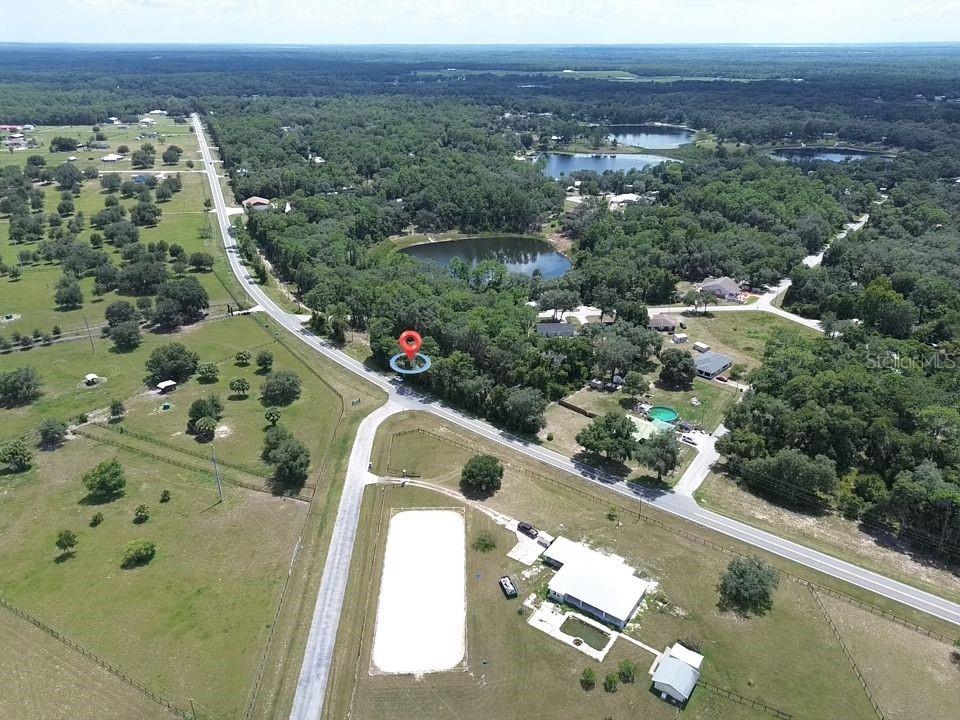 An aerial view shows a rural property with a house, riding arena, and nearby lakes — TBD SE 180TH AVE ROAD, OCKLAWAHA, FL