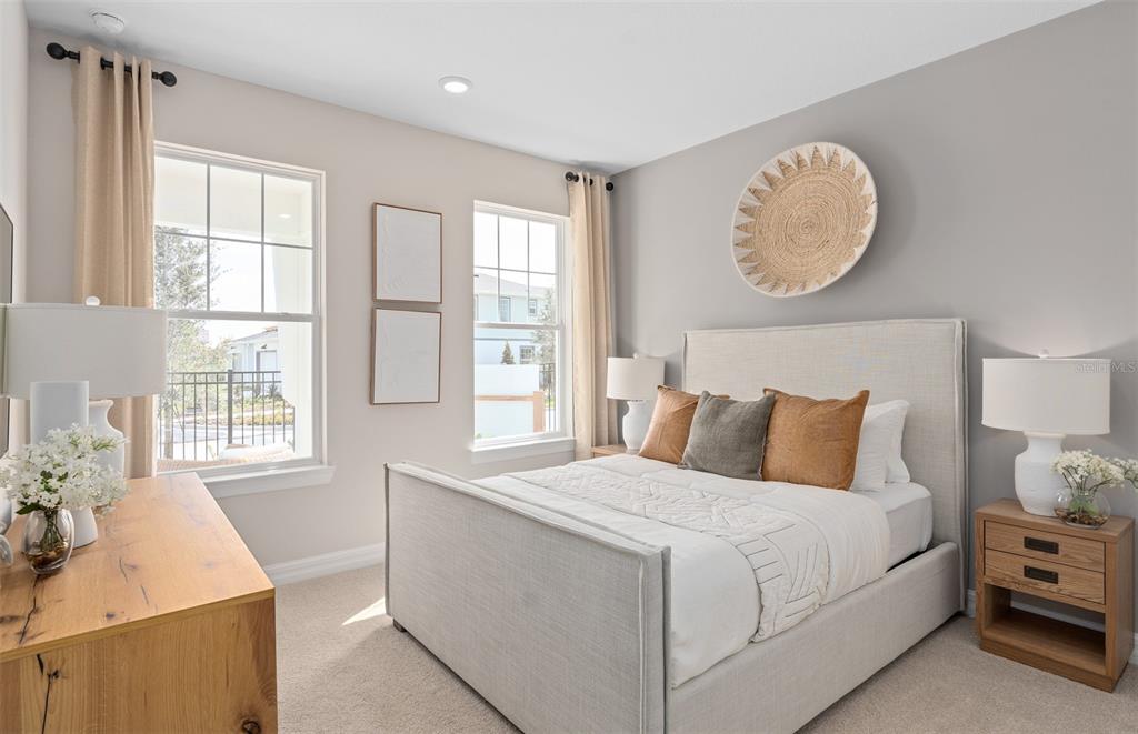 A bedroom features a light-colored upholstered bed, two nightstands, and two windows with curtains — 16449 LONE OAK CIRCLE, ORLANDO, FL