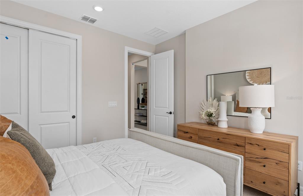 A bedroom features a bed, a wooden dresser with a mirror, and an open doorway — 16449 LONE OAK CIRCLE, ORLANDO, FL