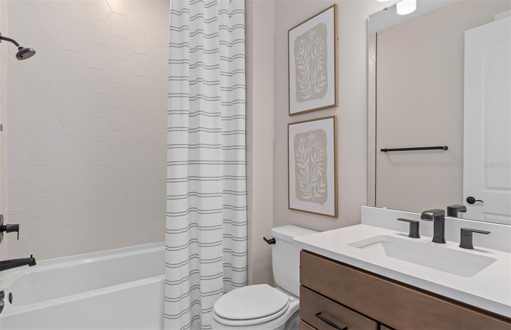 A bathroom features a tub with hexagon tile, a wood vanity, and a toilet — 16449 LONE OAK CIRCLE, ORLANDO, FL